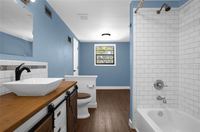 full bathroom featuring toilet, vanity, tiled shower / bath combo, and hardwood / wood-style flooring