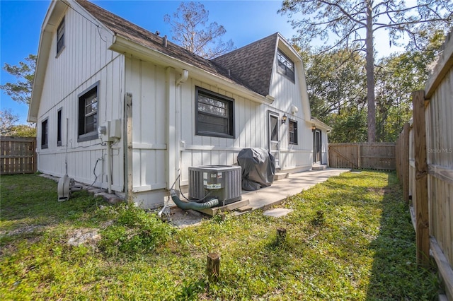 rear view of house with central air condition unit and a yard