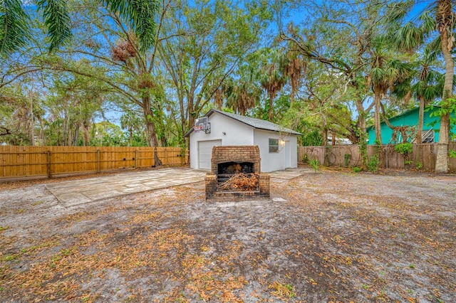 view of yard with an outdoor brick fireplace, an outdoor structure, and a garage