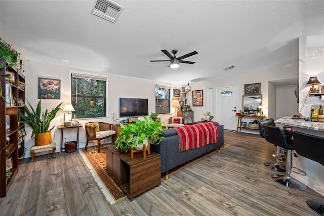 living room with hardwood / wood-style flooring, ceiling fan, and a textured ceiling