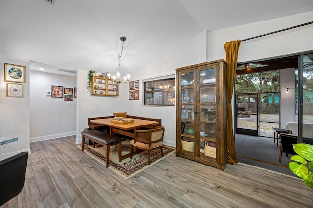 dining area with hardwood / wood-style floors, lofted ceiling, and a notable chandelier