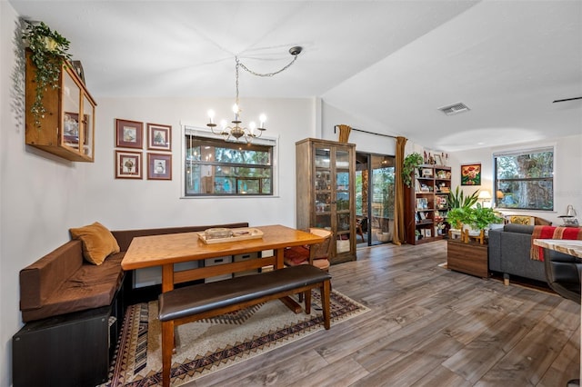 dining space with hardwood / wood-style flooring, lofted ceiling, and a chandelier