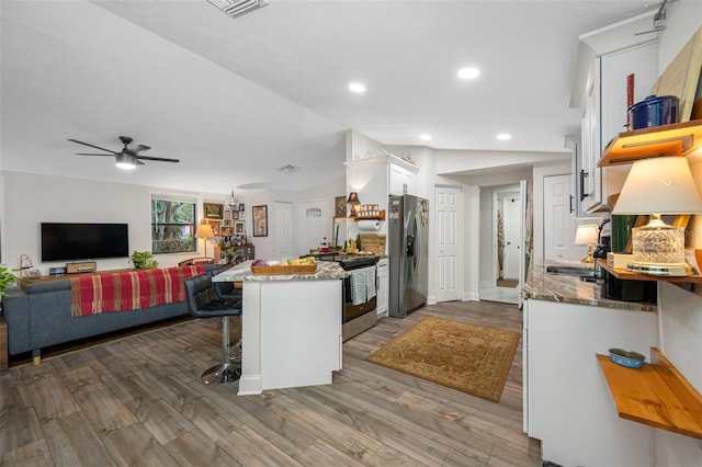 kitchen with white cabinetry, sink, stainless steel appliances, light stone counters, and a breakfast bar area