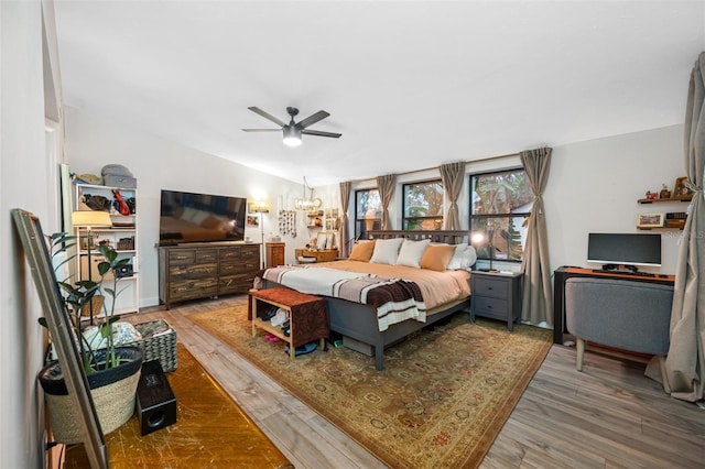 bedroom with ceiling fan with notable chandelier, wood-type flooring, and lofted ceiling