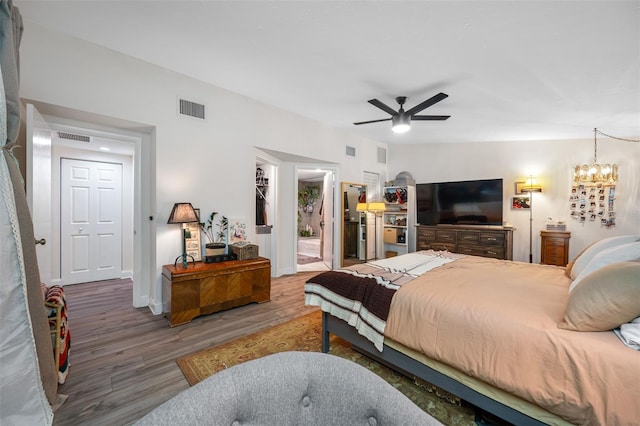 bedroom featuring hardwood / wood-style flooring, ceiling fan with notable chandelier, and a closet