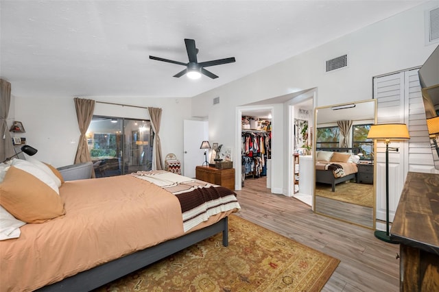 bedroom with hardwood / wood-style flooring, ceiling fan, a spacious closet, and a closet