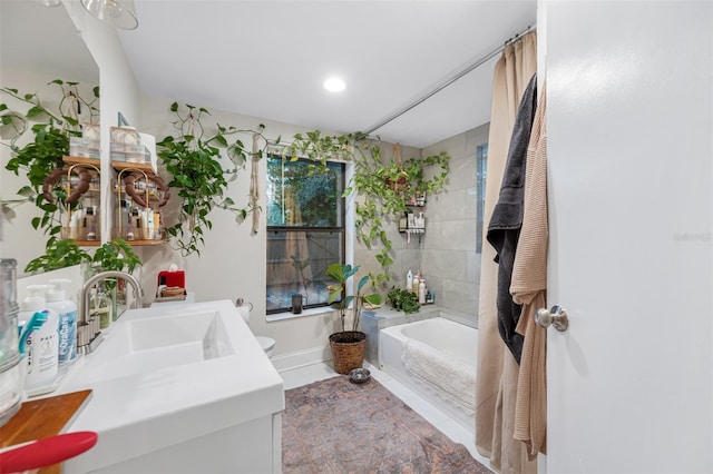 bathroom with a washtub, vanity, tile walls, and toilet