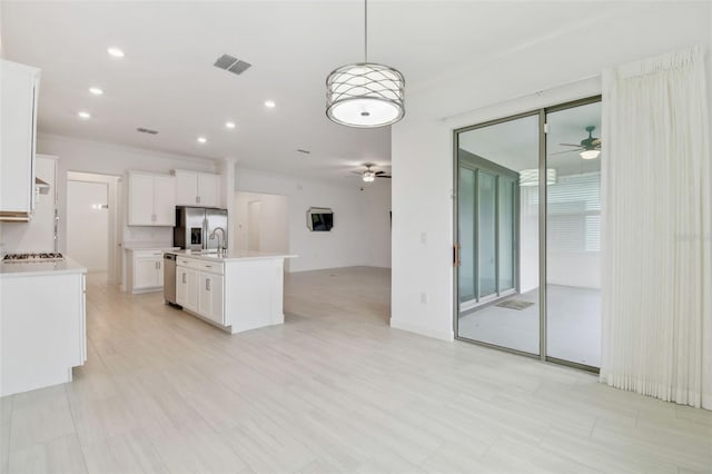 kitchen with appliances with stainless steel finishes, pendant lighting, white cabinets, a kitchen island with sink, and ceiling fan