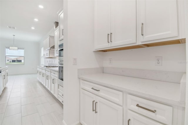 kitchen featuring decorative light fixtures, light tile patterned floors, white cabinets, light stone countertops, and exhaust hood