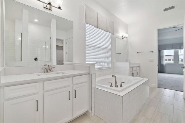 bathroom featuring tile patterned flooring, vanity, and tiled bath