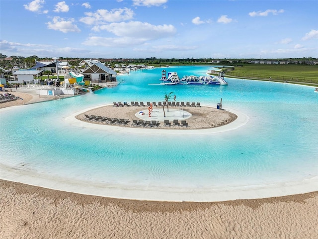 view of swimming pool featuring a water slide, a beach view, and a water view