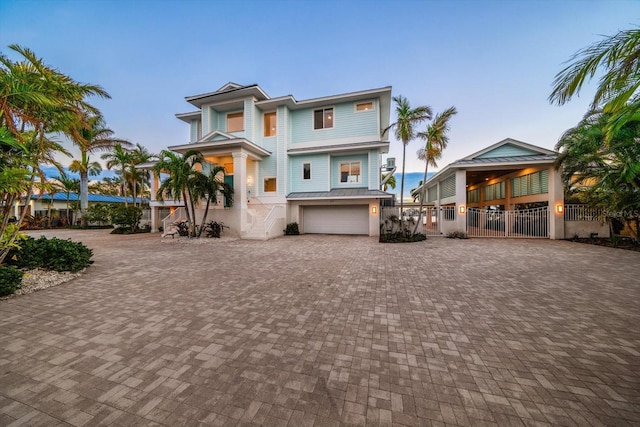 view of front of house featuring decorative driveway, an attached garage, and fence