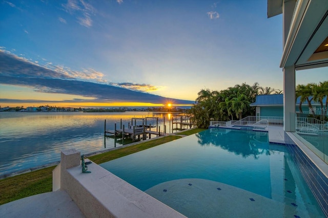 pool at dusk featuring a boat dock and a water view