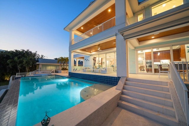 pool at dusk featuring a patio and ceiling fan