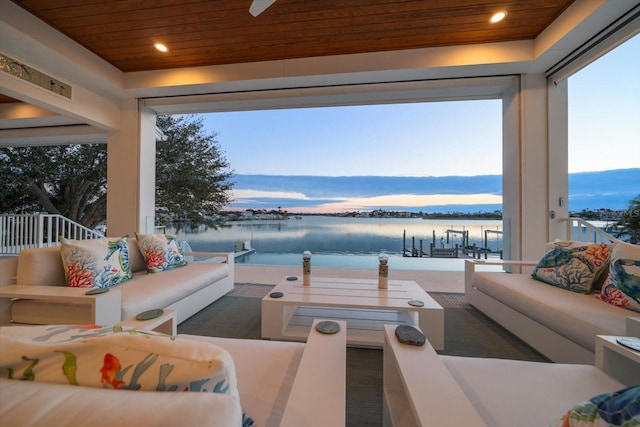 patio terrace at dusk featuring ceiling fan, a water view, and an outdoor hangout area