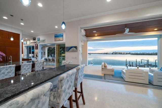 kitchen with ceiling fan, crown molding, a water view, and pendant lighting