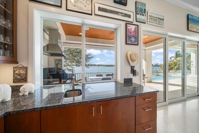 kitchen with island range hood, dark stone counters, and a water view