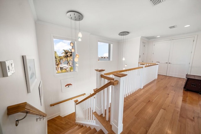 stairway with hardwood / wood-style flooring and ornamental molding