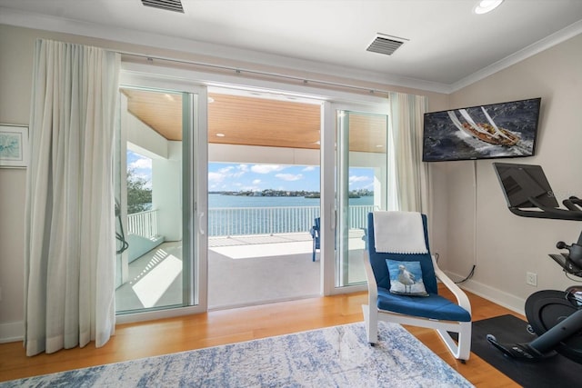 sitting room with a wealth of natural light, crown molding, a water view, and wood-type flooring