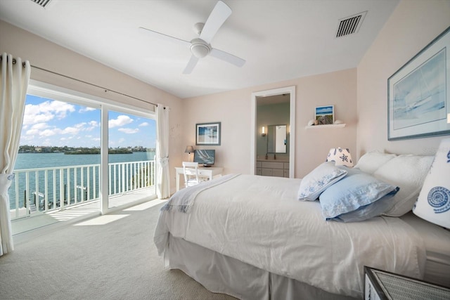 bedroom with access to exterior, carpet flooring, ensuite bath, ceiling fan, and a water view