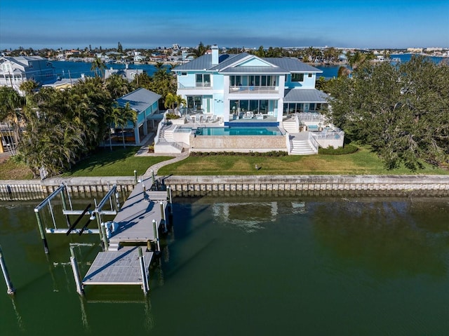 back of property with a water view, a balcony, and a patio