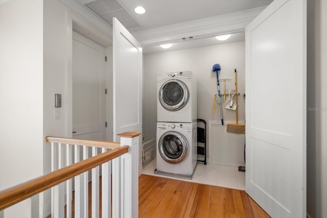 clothes washing area featuring light wood-type flooring and stacked washer and clothes dryer