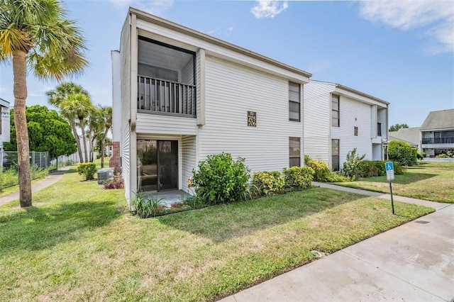 rear view of property featuring a balcony, central AC unit, and a lawn