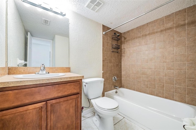 full bathroom featuring vanity, tile patterned floors, tiled shower / bath combo, toilet, and a textured ceiling