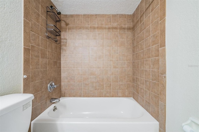 bathroom featuring tiled shower / bath combo, a textured ceiling, and toilet