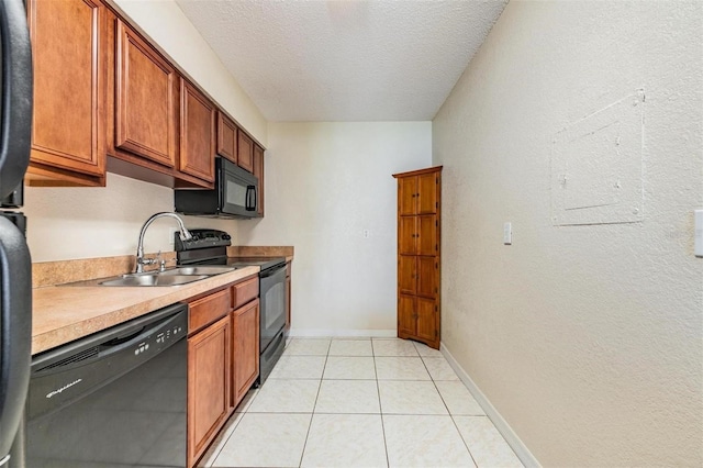 kitchen with a textured ceiling, sink, light tile patterned floors, and black appliances