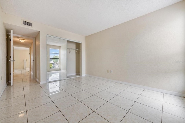 unfurnished bedroom featuring a closet, light tile patterned floors, and a textured ceiling