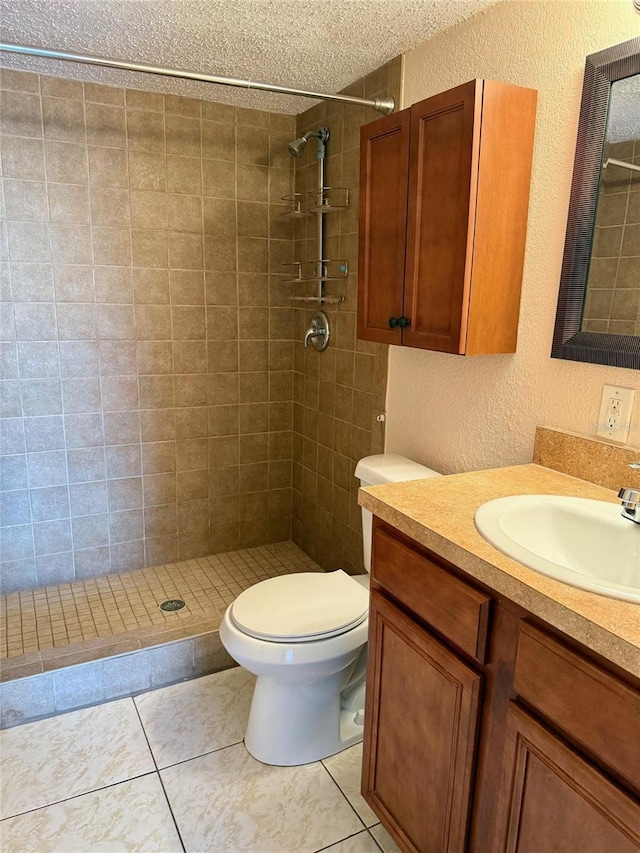 bathroom featuring a tile shower, tile patterned flooring, vanity, toilet, and a textured ceiling