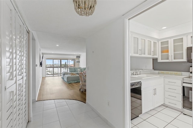 kitchen with range with electric stovetop, white cabinetry, light tile patterned flooring, black dishwasher, and sink