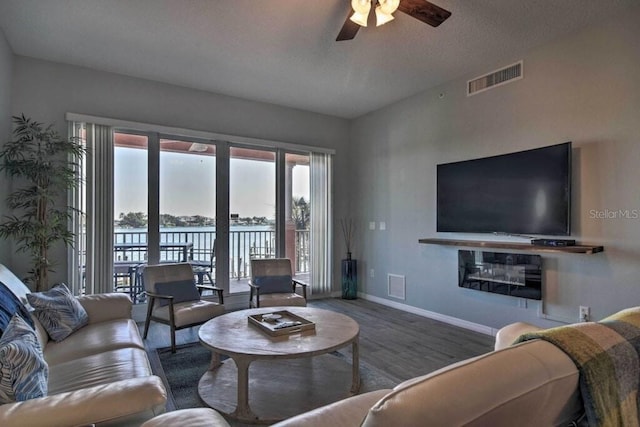living room featuring a textured ceiling, ceiling fan, and wood-type flooring