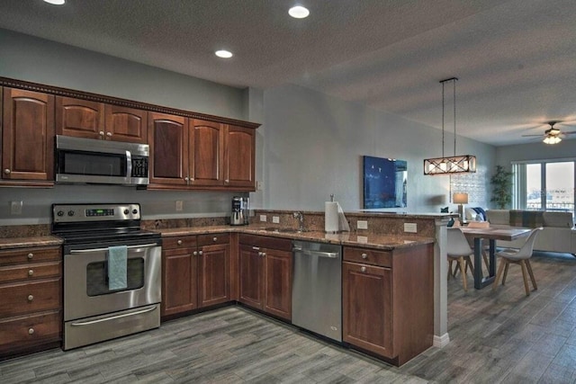 kitchen featuring ceiling fan, stainless steel appliances, kitchen peninsula, and hanging light fixtures