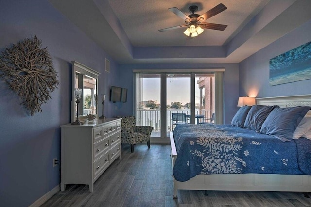 bedroom featuring ceiling fan, access to outside, a tray ceiling, and a textured ceiling