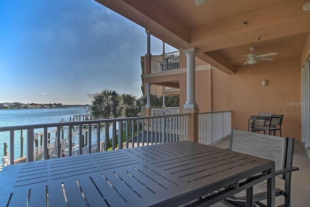 wooden terrace with a water view and ceiling fan
