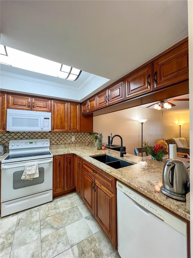 kitchen with white appliances, ceiling fan, ornamental molding, light stone counters, and sink