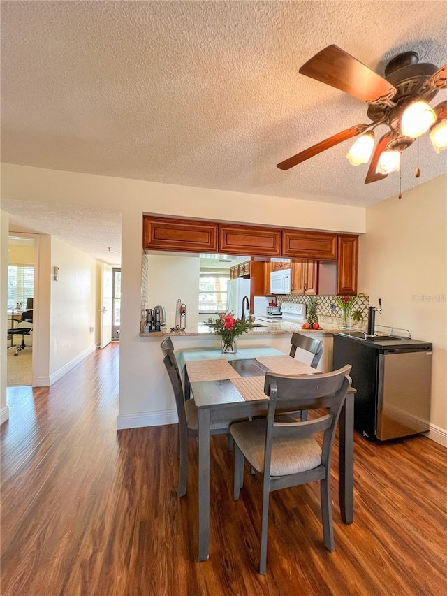 dining space with ceiling fan, dark wood-type flooring, and a textured ceiling