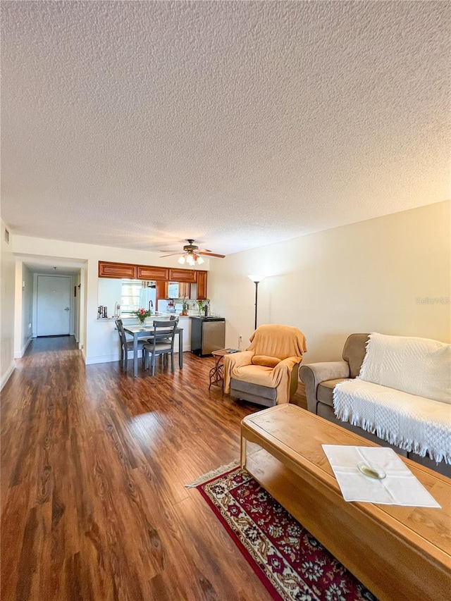 living room with ceiling fan, a textured ceiling, and wood-type flooring