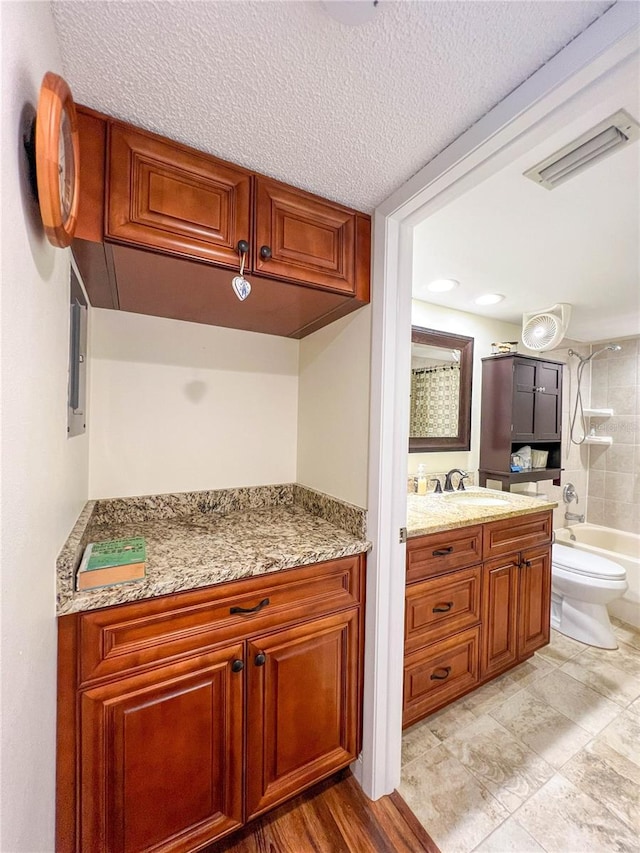 kitchen featuring light stone countertops, a textured ceiling, and sink