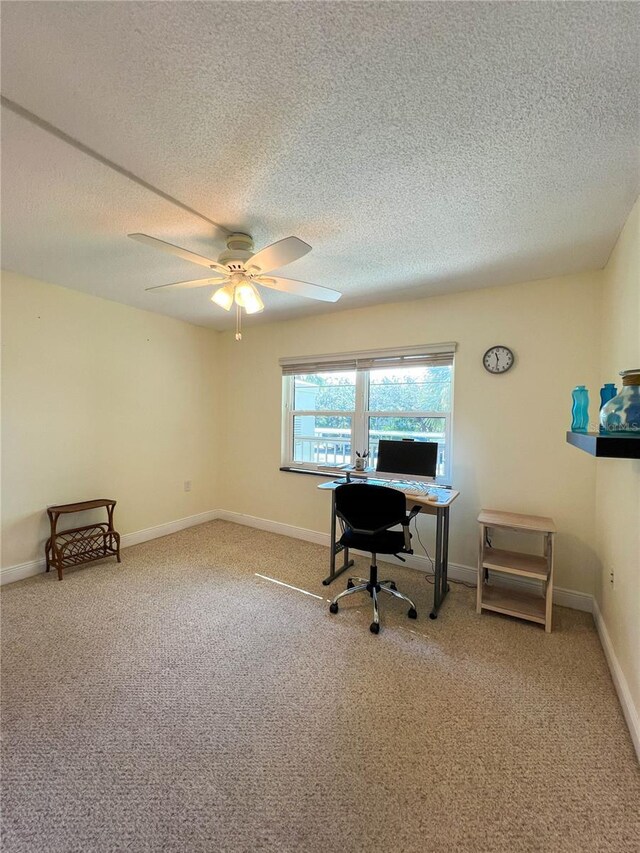 carpeted office featuring a textured ceiling and ceiling fan