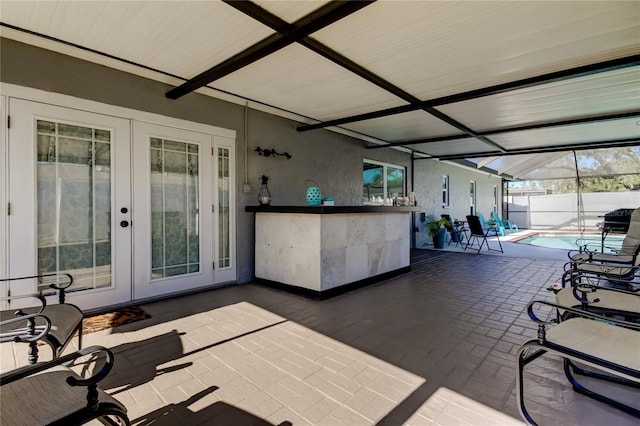 view of patio / terrace featuring a bar, a lanai, french doors, and a fenced in pool