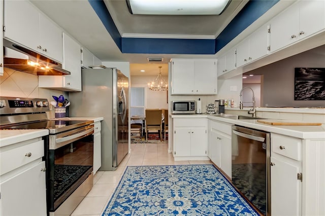 kitchen featuring stainless steel appliances, white cabinets, pendant lighting, and sink