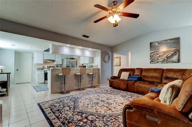 living room with lofted ceiling, ceiling fan, and light tile patterned floors