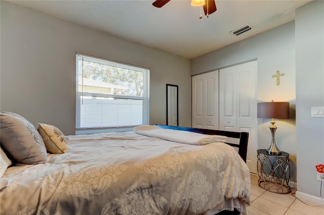 bedroom featuring ceiling fan, light tile patterned floors, and a closet