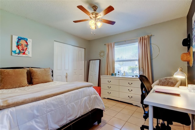 bedroom featuring a textured ceiling, a closet, ceiling fan, and light tile patterned floors