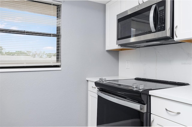 kitchen featuring range with electric stovetop and white cabinets