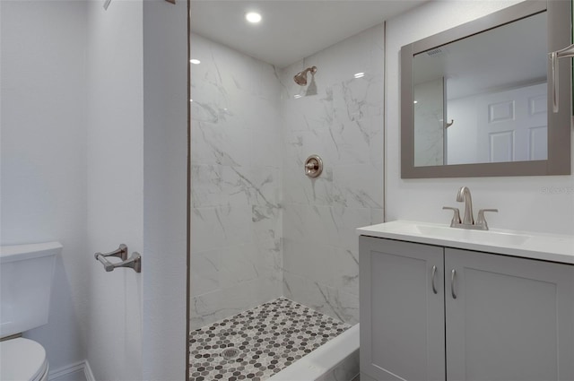 bathroom featuring toilet, tiled shower, and vanity