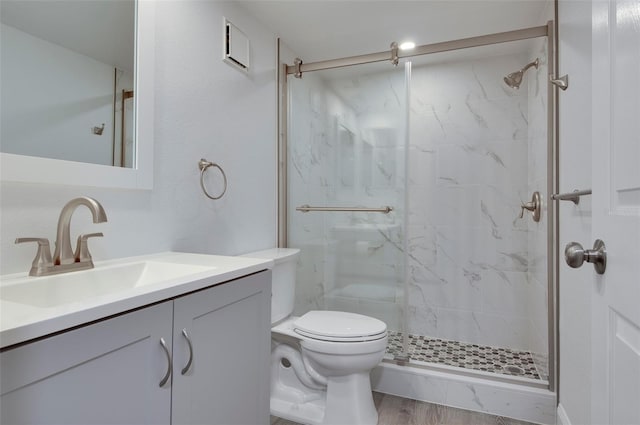 bathroom featuring toilet, vanity, wood-type flooring, and a shower with door